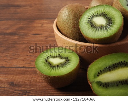 Ripe fresh oval kiwifruit on a wood background. It has fibrous, bright green flesh and edible black seeds. A sweet and unique taste.It is a natural, healthy and nutritious food.With copy space.