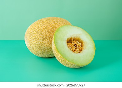 Ripe Gaul melons. A melon split in half showing its seeds on a plain green background
