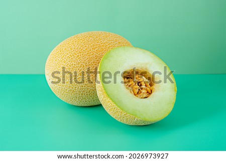 Ripe Gaul melons. A melon split in half showing its seeds on a plain green background