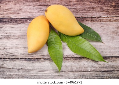 Ripe golden mangos with leaf on wood.