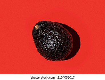 Ripe haas avocado on a red background from above. Creative food composition. Flat lay, avocado isolated on background. Pop art design, tropical summer abstract background with avocado.
