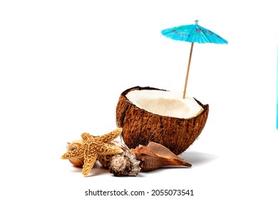 A Ripe Half Coconut With Sea Shells And A Cocktail Umbrella Suggesting Making A Tropical Drink Like A Pina Colada Isolated On White