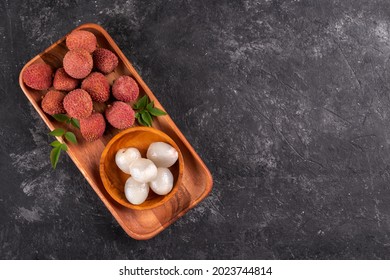 Ripe healthy lychee fruit in a wooden bowl on black stone background with copy space