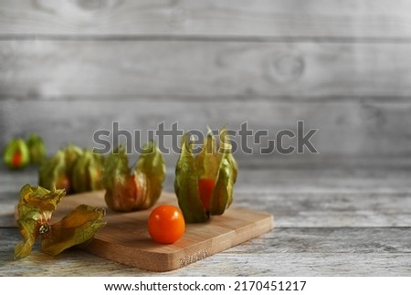 Ripe healthy physalis over wooden board on a wooden background, copy space. The fruits of physalis contain pectin, useful fatty oils, organic acids (tartaric, coffee, citric, synaptic, apple, amber
