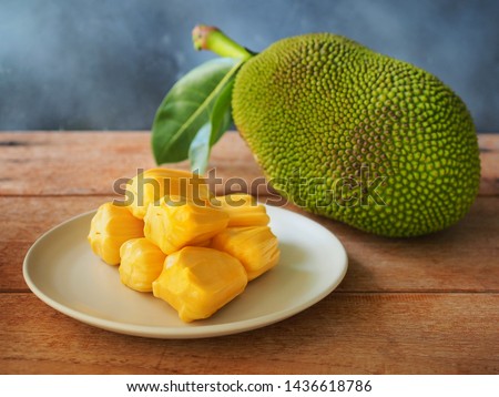 Ripe jackfruit flesh in white plate on wooden table for tropical fruit or meat substitute concept.