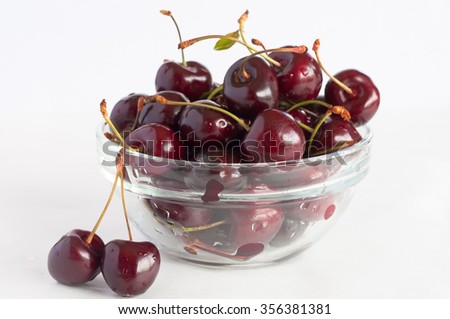 ripe and juicy cherries in a glass bowl on a white background close-up