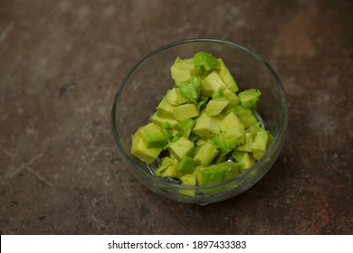 Ripe Juicy Diced Avacado In A Transparent Bowl On A Granite Table.