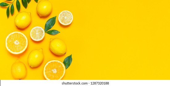 Reife saftige Zitronen, orangefarbene und grüne Blätter auf hellgelbem Hintergrund. Zitronenfrüchte, Zitrusminimalkonzept, Vitamin C. Kreativer Sommer minimalistischer Hintergrund. Flachlage, Draufsicht, Kopienraum. 