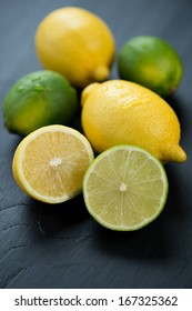 Ripe lemons and limes over black wooden background