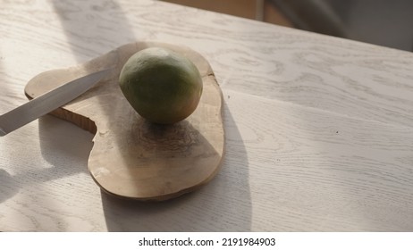 Ripe Mango On Olive Board With Knife On White Oak Table