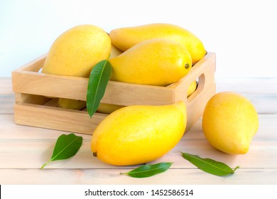 Ripe mangos and leaves in a basket on woodren floor on white background