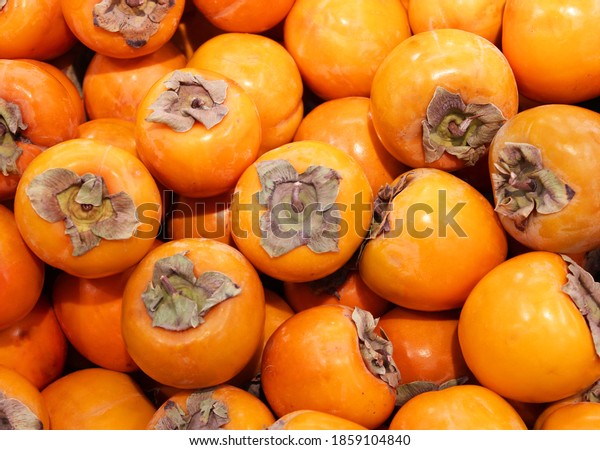Ripe orange\
persimmons. on the table in the market. A bunch of organic\
persimmon fruits at a local farmers market. Persimmon background.\
Flat lay. Copy space for text and\
content.