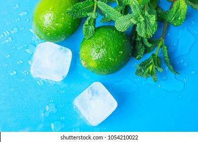 Ripe Organic Limes Fresh Spearmint Melted Ice Cubes on Light Blue Background with Water Drops. Mojito Cocktail Ingredients. Vibrant Colors Funky Style. Summer Freshness Concept. Copy Space 
