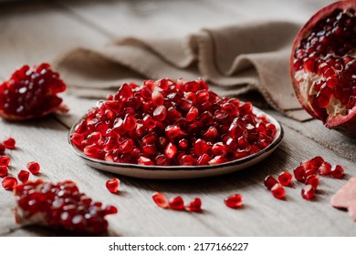 ripe peeled pomegranate on a wooden background, pomegranate seeds on a plate - Powered by Shutterstock