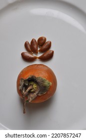 Ripe Persimmon And Persimmon Seeds On A White Dish Macro