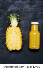 Ripe Pineapple And Bottle Of Juice Over Black Background. Top View