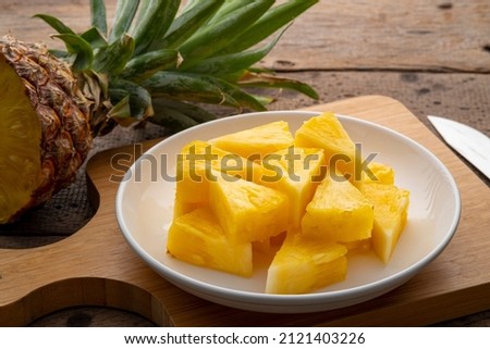 Ripe pineapple slice on white plate on a wooden table