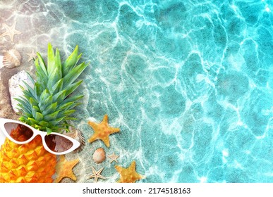 Ripe pineapple in stylish sunglasses and seashells in blue sea, relaxing. Tropical summer vacation concept.