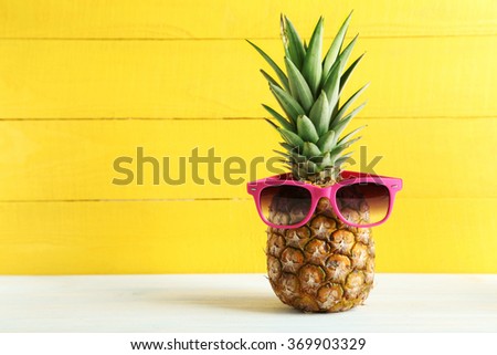 Ripe pineapple with sunglasses on a white wooden table