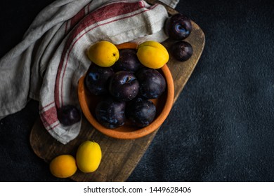 Ripe ploom fruits in a bowl on vintage cutting board with copy space - Shutterstock ID 1449628406