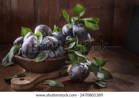 Ripe plum on dark wooden background in rustic style