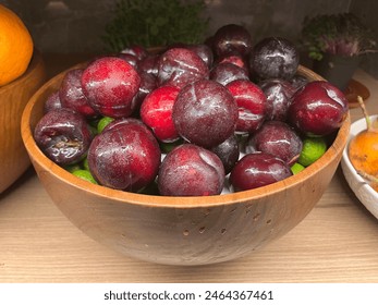 Ripe plums and leaves in a wooden bowl on the table - Powered by Shutterstock