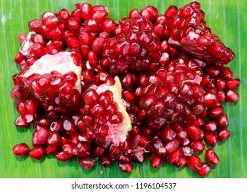 Ripe pomegranate fruit on green banana leaf background. top view. Pomegranate juice contains higher levels of antioxidants than most other fruit juices.  