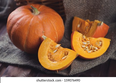 Ripe pumpkin and its slices on a bagging cloth, studio shot