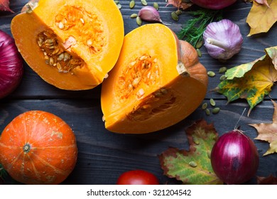Ripe pumpkins and autumn leaves on wooden background