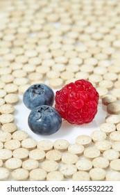 Ripe Raspberries And Blueberries Are Surrounded By Pills On All Sides. Concept: Natural Vitamins. Close Up.