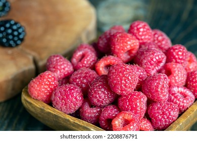 Ripe raspberries on the table, raspberries in a wooden bowl and on a board - Shutterstock ID 2208876791