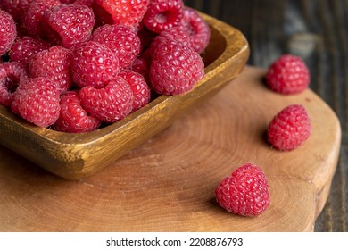 Ripe raspberries on the table, raspberries in a wooden bowl and on a board - Shutterstock ID 2208876793