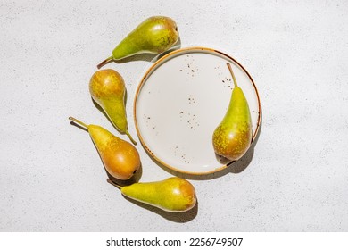 Ripe raw pears on a plate on a white concrete background - Shutterstock ID 2256749507