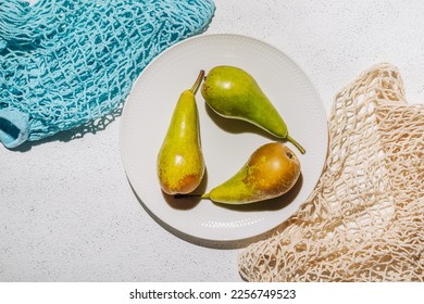 Ripe raw pears on a plate on a white concrete background - Shutterstock ID 2256749523
