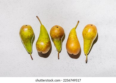Ripe raw pears in a row on a white concrete background - Shutterstock ID 2256749517
