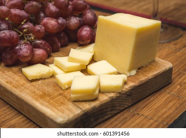Ripe Red Grapes And White Cheese On A Wood Block.