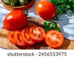Ripe red Roma tomatoes in bowl with fresh herbs on table