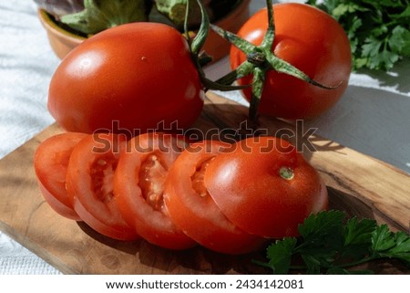 Ripe red Roma tomatoes in bowl with fresh herbs on table