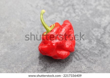 Ripe red scotch bonnet peppers against a gray patterned background