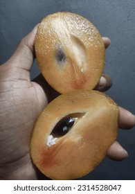 Ripe sapodilla fruit is split into 2 and eaten sweet