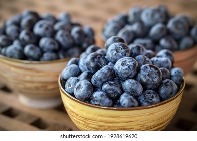 Ripe, sweet blueberries in yellow ceramic bowl on wooden table for healthy nutrition. 
