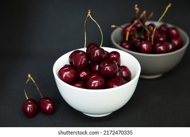 Ripe sweet cherries in a white bowl. Grey background.