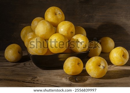 ripe sweet yellow plums in black ceramic bowl  close up