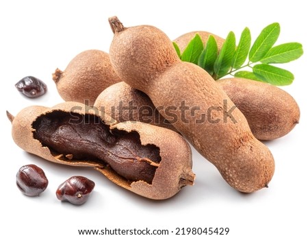 Ripe tamarind fruit, leaves and some tamarind seeds isolated on white background.
