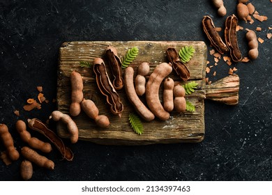 Ripe Tamarind On A Kitchen Wooden Board. On A Stone Background. Top View.