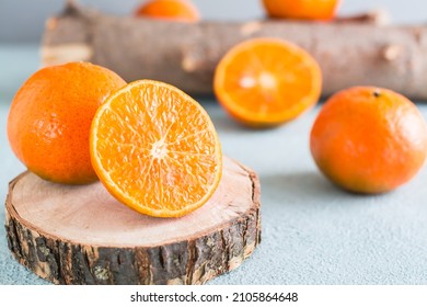 Ripe tangerine cut in half on a tree saw cut and tangerines nearby on a blue background. Eco-friendly fruits. Close-up