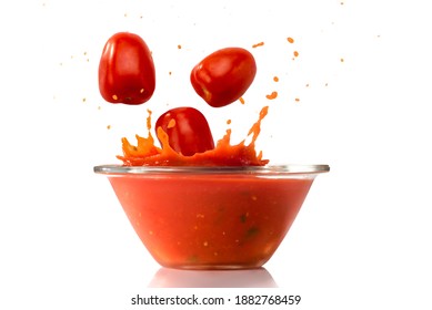 Ripe Tomatoes Fall Into Glass Bowl With Splashing Red Tomato Sauce, Isolated On White Background