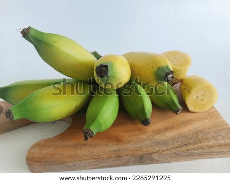 ripe and unripe bananas with slices arranged on a wooden cutting board