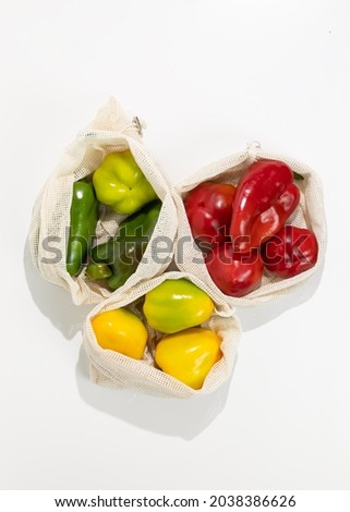 Ripe yellow, green and red bell pepper lies in a fabric net string bag. Ecology concept, zero waste, no plastic. Shopping local seasonal vegetables.