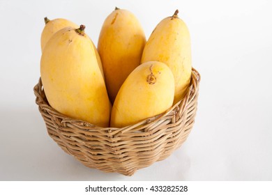 Ripe yellow mangoes placed in a basket on a white background.